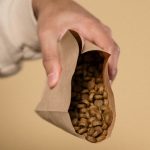 茶色い紙袋からドッグフードの粒をのぞかせて持つ手